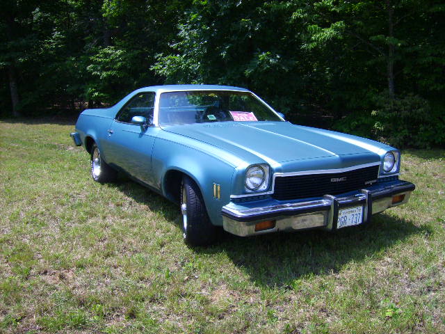 Light blue 1970s GMC coupe-utility pickup, 3/4 front view on grass