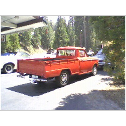 1973 Ford Ranchero - A red 1973 Ford Ranchero pickup truck is parked next to another vehicle under a covered area.