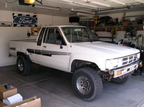 1986 Toyota Hilux - A white pickup truck is parked inside a garage with its front bumper removed.