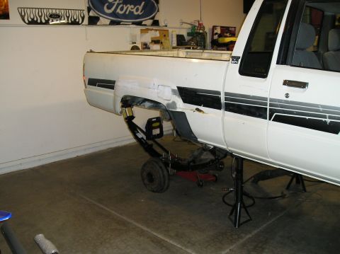 1986 Toyota Hilux - Rear suspension of a white 1986 Toyota Hilux is visible as it is being worked on in a garage.