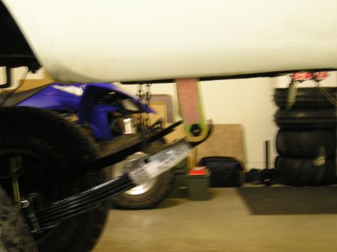 1986 Toyota Hilux - Close-up of a vehicle's leaf spring suspension system, with a blue ATV in the background.