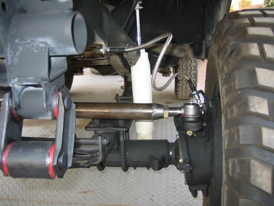 Front axle close-up with heavy tie rod, braided brake line and steering stabilizer