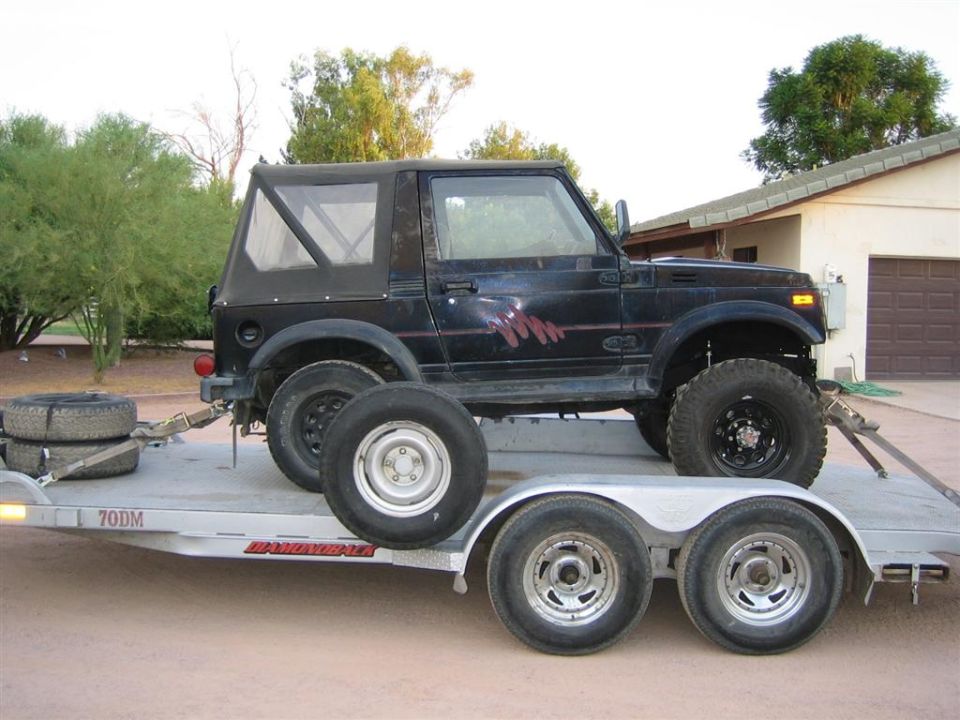 Lifted black Suzuki Samurai soft-top loaded on an aluminum tandem-axle car trailer