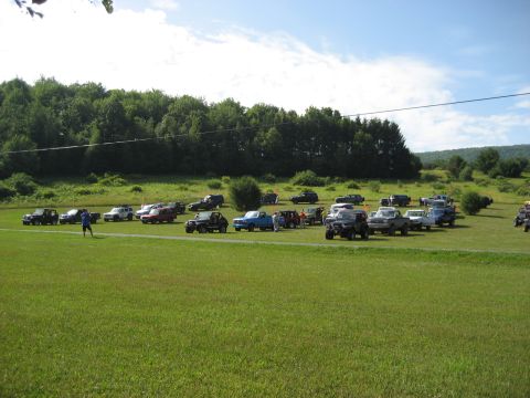 1991 Ford Bronco - Many different types of trucks and SUVs are parked in a large, open field on a sunny day.