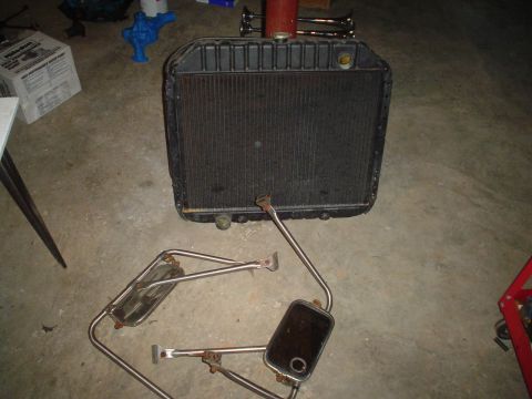 1967 Ford F-250 - A radiator and two side mirrors are laid out on a concrete floor, possibly for restoration or sale.