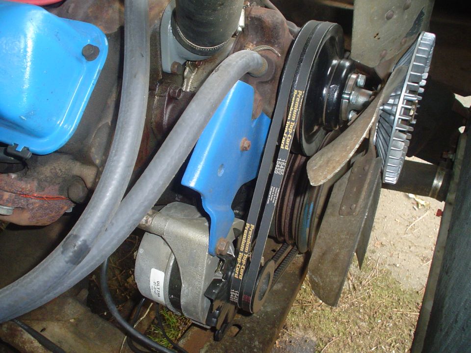 Engine belts and fan blades with blue brackets and a silver alternator