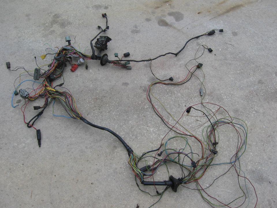 Vehicle wiring harness spread out on concrete. Lots of colored wires and connectors