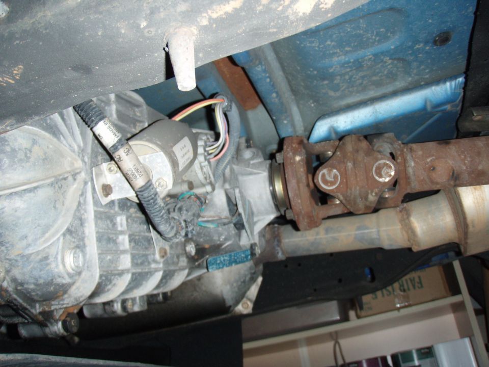 Underside view of vehicle driveshaft, U-joint, and transmission housing with wiring