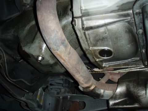 1996 Ford Bronco - Undercarriage view showing the exhaust system and transmission housing, with visible oil residue.