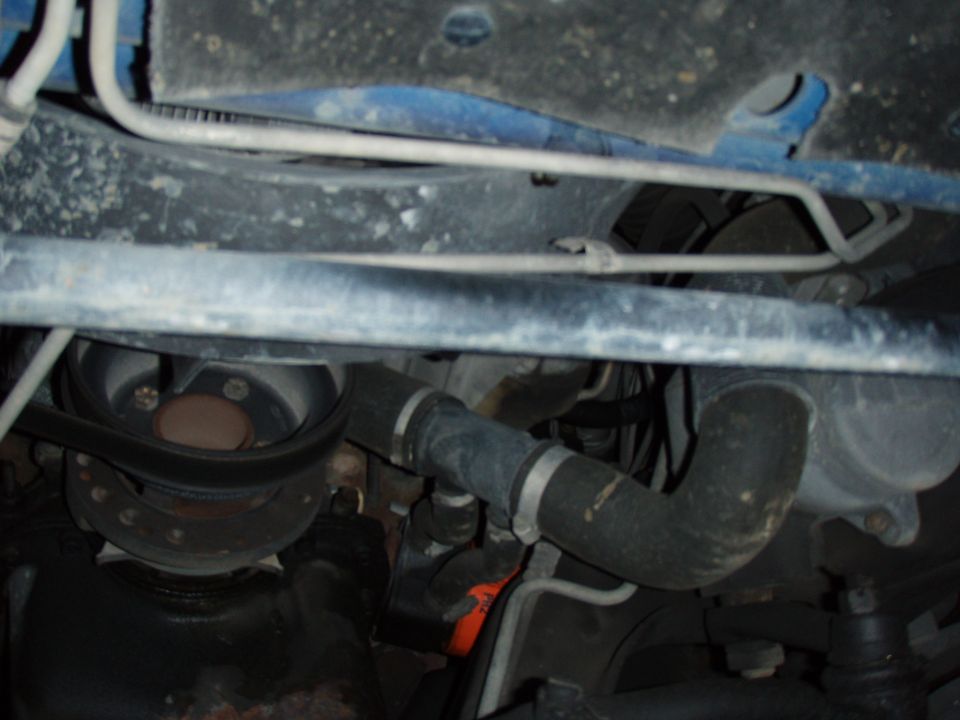 Undercarriage view of a vehicle, showing hoses, belts, and frame components. Watermark says www.supermotors.net