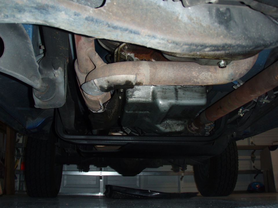 Undercarriage of a 1996 Ford Bronco showing exhaust pipes, oil pan, and driveshaft