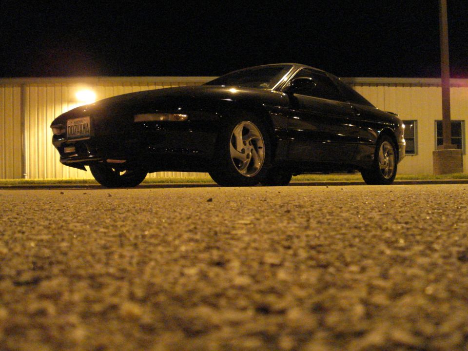 Black Ford Probe coupe at night, low front three-quarter angle lit by floodlight