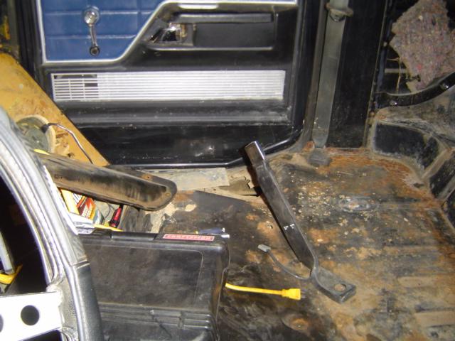 1979 Ford Bronco interior showing rusted floor, door panel, and dashboard components