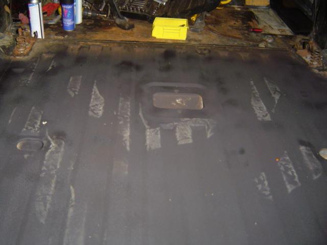 Interior floor of a vehicle, looks like it's being prepped for something. Tools and cans are on a surface behind it