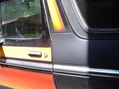 1979 Ford Bronco - Detail of a vintage SUV's side door, distinctive yellow and orange graphics and a chrome door handle.