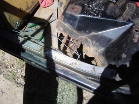 1979 Ford Bronco - Close-up of a heavily rusted car door interior, showing exposed wires and a pair of pliers.