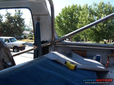 1996 Ford Bronco - View from inside a vehicle with a roll cage, looking out at a white 1996 Ford Bronco parked on a street.