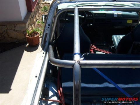 1996 Ford Bronco - The interior of the vehicle shows a custom roll cage and racing seats, with a jack visible on the floor.