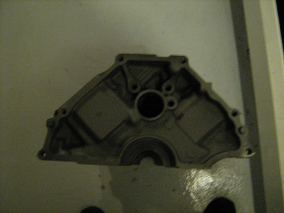 Aluminum engine timing cover lying on a workbench