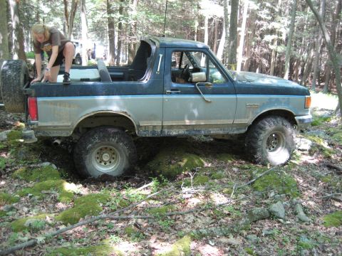 1991 Ford Bronco - A 1991 Ford Bronco navigates a rocky, wooded trail during an off-road excursion.
