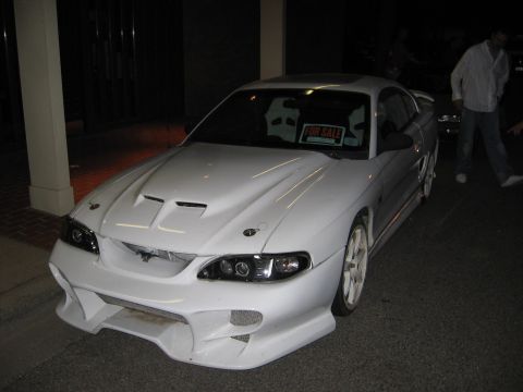 1989 Ford Mustang - This modified Ford Mustang features a custom front bumper, hood, and racing seats, with a "For Sale" sign in the window.
