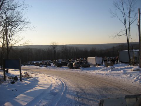 1991 Ford Bronco - A winter scene shows a variety of vehicles parked in a snow-covered lot with trees and hills in the background.