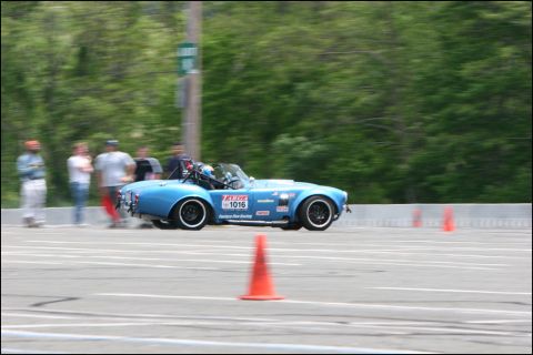 2001 Mercury Grand Marquis - A blue convertible race car navigates a track, with spectators blurred in the background.
