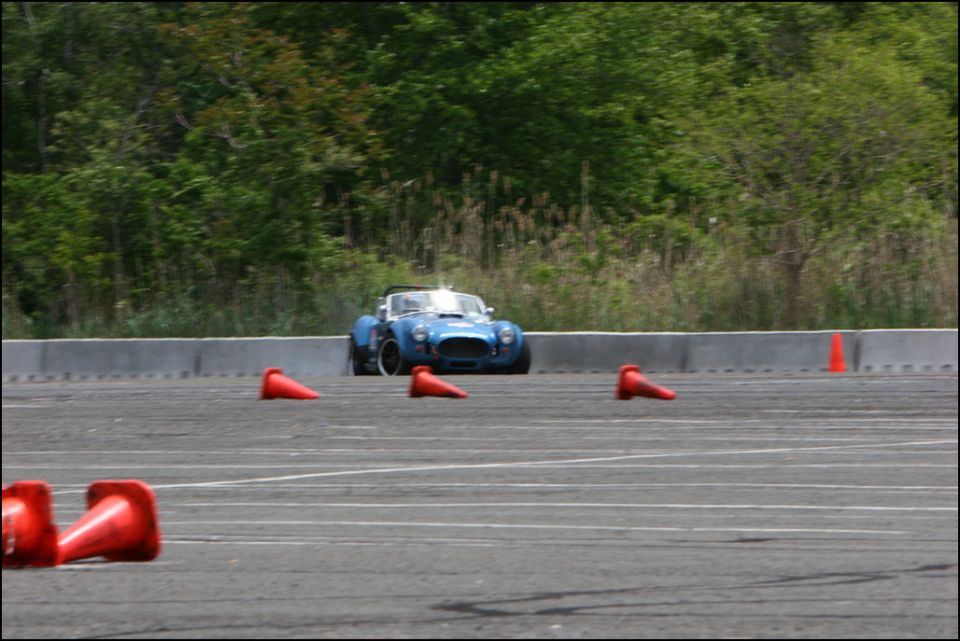 Blue AC Cobra replica with white stripes navigating an autocross course