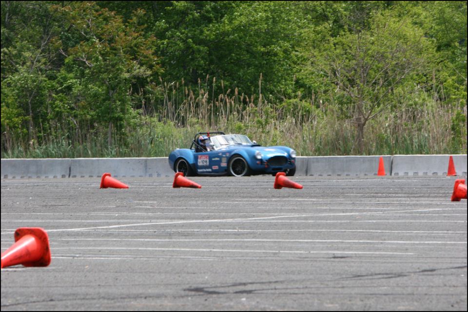 Blue convertible sports car with racing decals on a track with orange cones