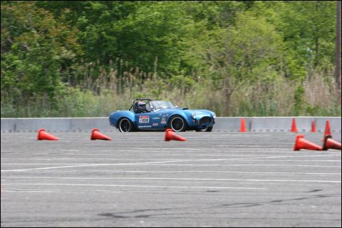 2001 Mercury Grand Marquis - A blue convertible sports car, likely a Cobra replica, navigates an autocross course marked by orange cones.