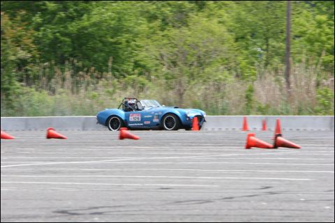 2001 Mercury Grand Marquis - A blue convertible race car is seen on an autocross course, marked by orange cones.