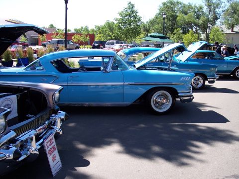 1972 Ford Ranchero - A line of classic blue cars, including a 1957 Chevrolet, are parked with hoods open at an outdoor event.