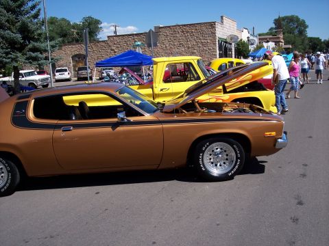 1972 Ford Ranchero - A brown 1972 Ford Ranchero with racing stripes and custom flames on the hood is displayed at an outdoor event.