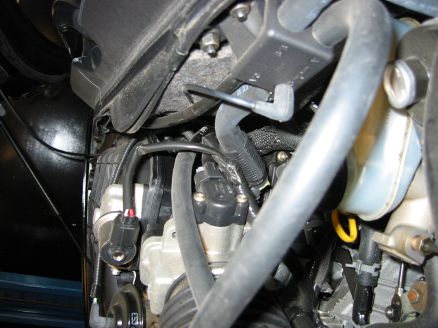 Under-hood close-up of throttle body, intake housing, hoses, and brake master cylinder reservoir