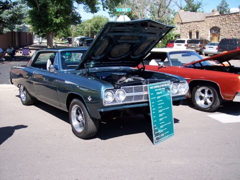 1972 Ford Ranchero - A teal 1965 Chevrolet Malibu SS is displayed with its hood open, next to a red car.