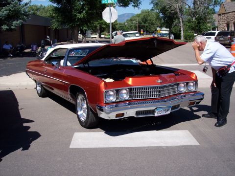 1972 Ford Ranchero - Man inspects the engine of a 1971 Chevrolet Caprice Convertible at an outdoor event.