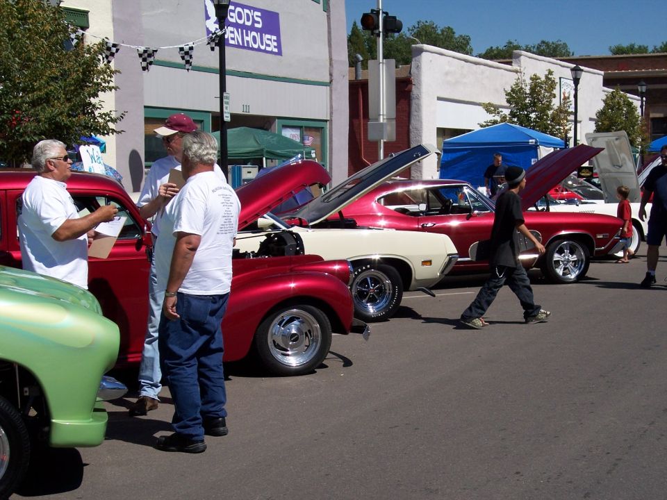 Red and cream muscle car with hood open, parked on street next to other vehicles