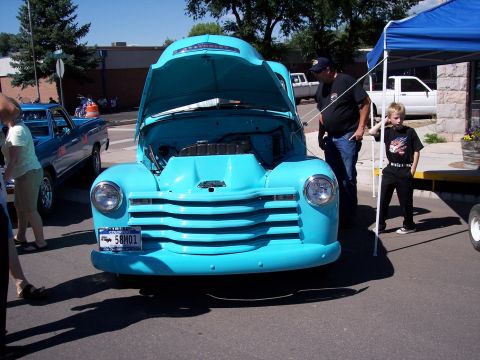 1972 Ford Ranchero - A turquoise Chevrolet truck with its hood open is displayed, with a blue pickup truck visible in the background.