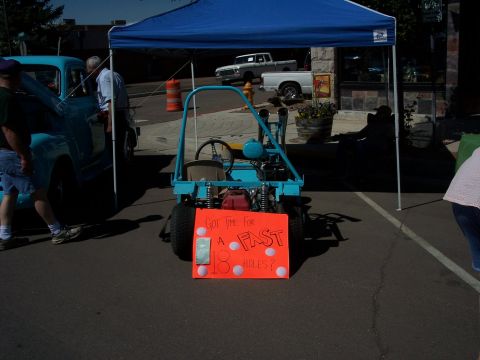 1972 Ford Ranchero - A go-kart with a sign about playing golf is displayed next to a vintage pickup truck.