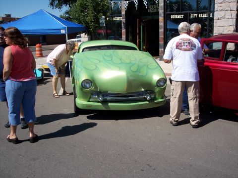 1972 Ford Ranchero - A green custom hot rod with flame graphics is parked on a street next to a red car.