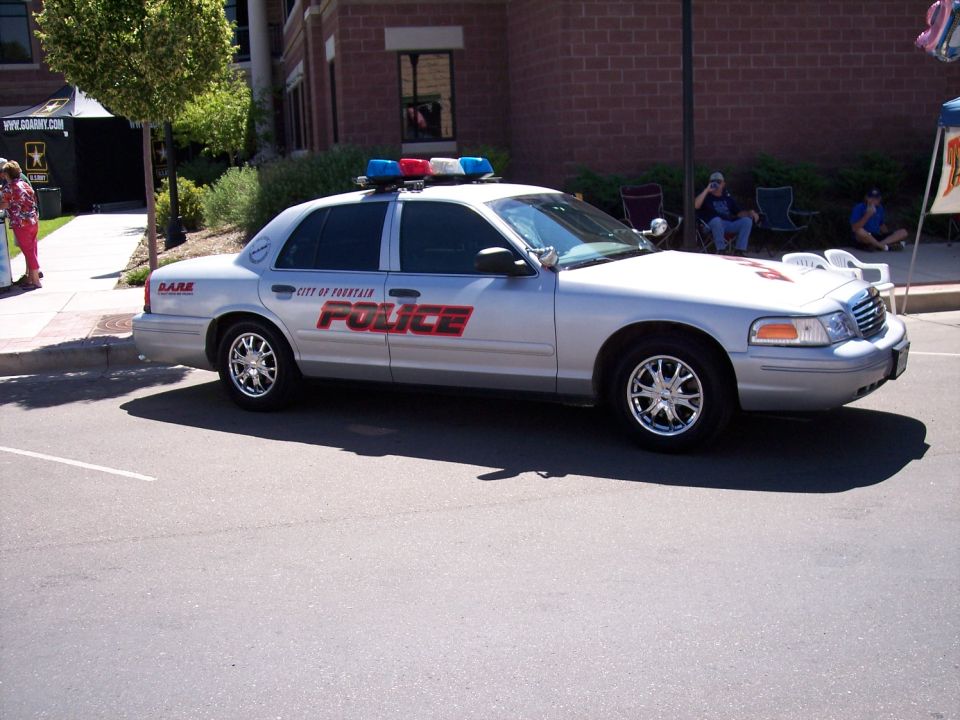 Silver police car with red 'POLICE' text and 'CITY OF FOUNTAIN' on the side, equipped with a light bar