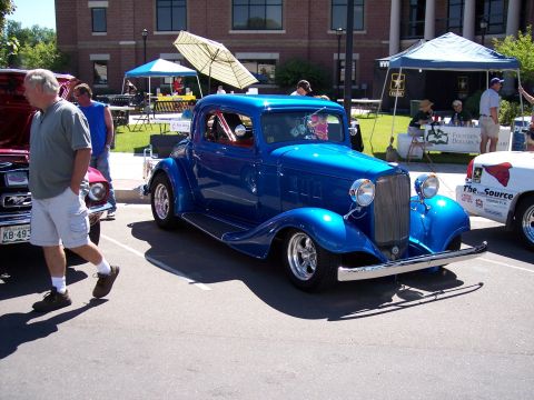 1972 Ford Ranchero - A blue coupe hot rod is displayed at an outdoor car show with tents and people around.