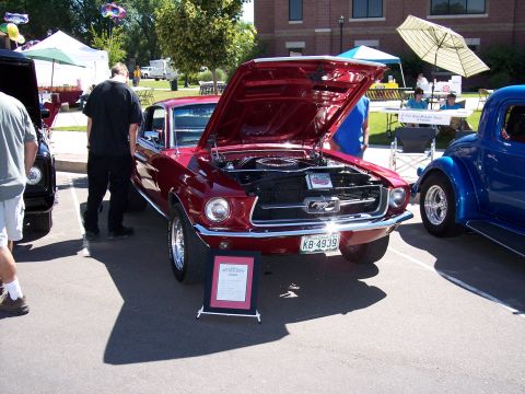 1972 Ford Ranchero - A classic red Ford Mustang is displayed with its hood open at an outdoor event, alongside other vehicles.