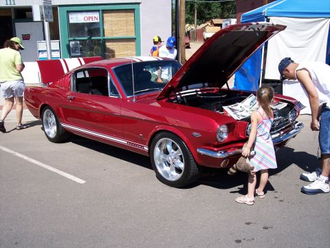 1972 Ford Ranchero - Classic red Ford Mustang coupe on display, with people admiring its engine.