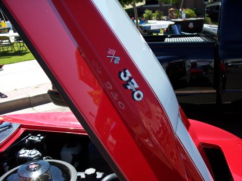 1972 Ford Ranchero - Close-up of a red car's hood racing stripes and a '370' emblem, with a black truck in the background.