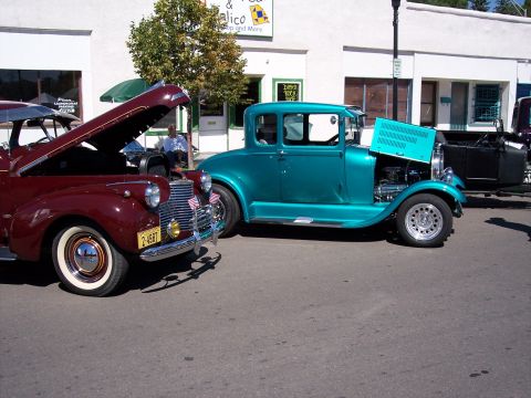 1972 Ford Ranchero - A maroon car and a teal car are parked side-by-side on a street, both with their hoods open.