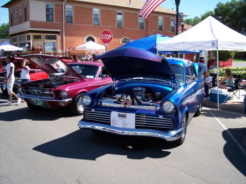 1972 Ford Ranchero - Two classic cars, a blue sedan and a pink Ford Mustang, displayed with hoods open at an outdoor event.
