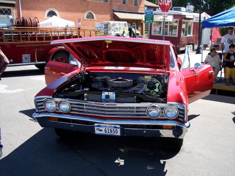 1972 Ford Ranchero - A bright red 1965 car is displayed with its hood open, revealing the engine and front grille. The Colorado license plate reads 61N50.