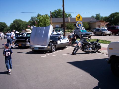 1972 Ford Ranchero - A two-tone 1980s Chevrolet Corvette is displayed with its hood open at an outdoor event.