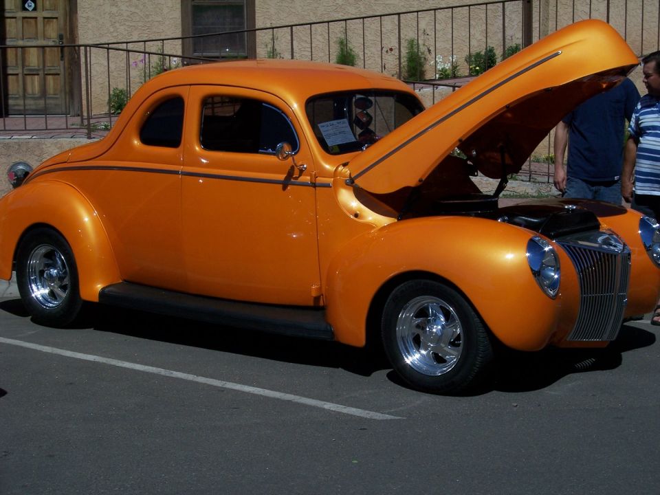 Orange 1940s coupe with hood open, chrome grille and wheels
